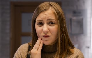 woman holding her cheek with mouth pain